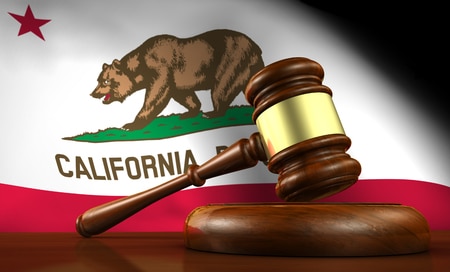 california law, legal system and justice concept with a 3d render of a gavel on a wooden desktop and the californian flag on background.