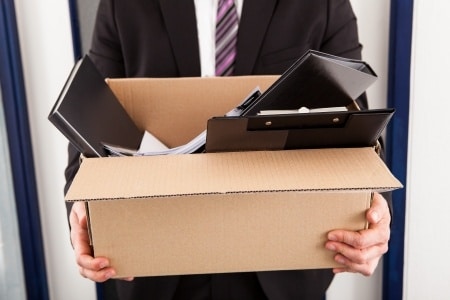 portrait of young businessman holding cardboard in office