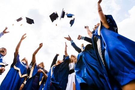 image of happy young graduates throwing hats in the air