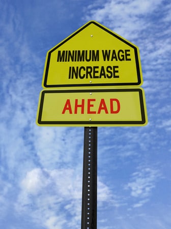 conceptual sign with words minimum wage increase ahead over blue sky