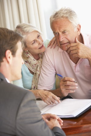 senior couple meeting with financial advisor at home looking worried