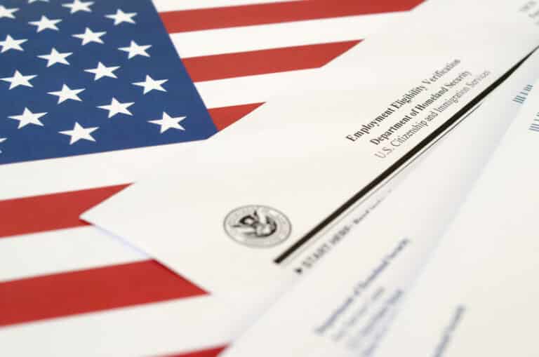 I-9 Employment Eligibility Verification blank form lies on United States flag with envelope from Department of Homeland Security close up