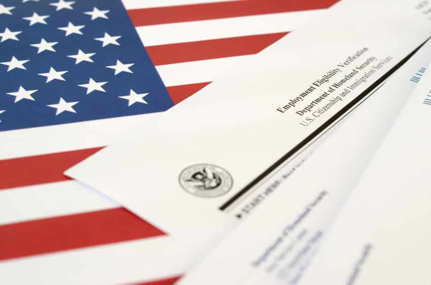 I-9 Employment Eligibility Verification blank form lies on United States flag with envelope from Department of Homeland Security close up