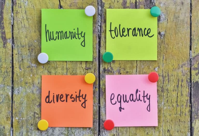 Four stickers with handwritten text about human tolerance pinned on wooden background