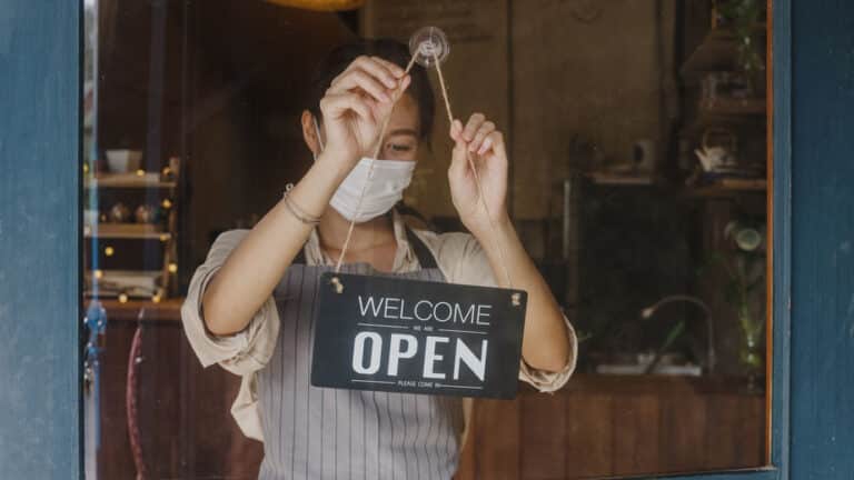 Young girl wear face mask turning a sign from closed to ope